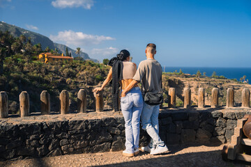 A young couple enjoys a scenic view from a stone terrace on Tenerife, with a backdrop tranquility...