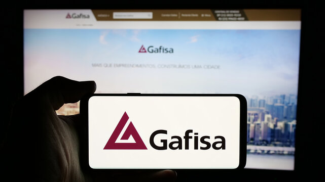 Stuttgart, Germany - 12-18-2024: Person holding cellphone with logo of Brazilian real estate company Gafisa SA on screen in front of business webpage. Focus on phone display.