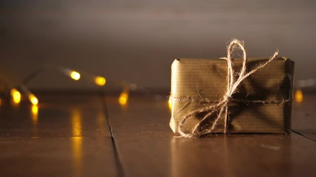 Gift wrapped in brown paper and string with Christmas lights bokeh background