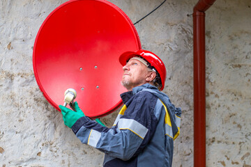 A worker installs an MTS satellite TV antenna to receive a signal. Satellite TV