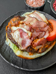 Juicy burger with beef patty, tomatoes, cheese, bacon, salt and spices