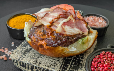 Juicy burger with beef patty, tomatoes, cheese, bacon, salt and spices