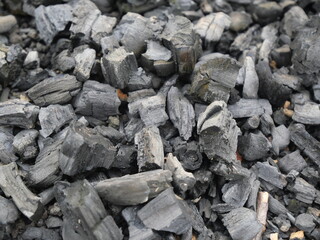 wood charcoal with a beautiful natural background. Pile of natural wood charcoal isolated on black sand background. Hardwood charcoal.