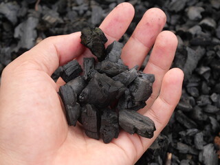 wood charcoal with a beautiful natural background. Pile of natural wood charcoal isolated on black sand background. Hardwood charcoal.