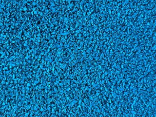 Close-up of a textured surface made of small, vibrant blue rubber granules