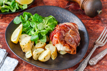 Prosciutto wrapped chicken with herby potatoes and green lettuce