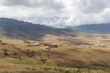 Scenic view of traditional Masai village surrounded by mountains in Serengeti Tanzania East Africa