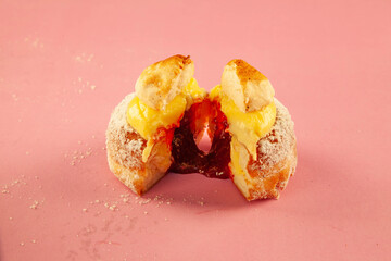 Scone donuts with strawberry jelly and meringue and vanilla custard on a pink background.
