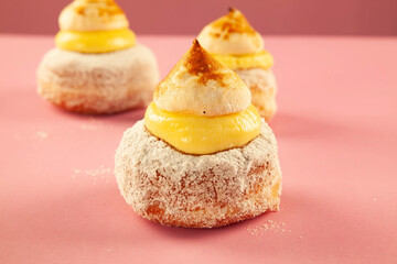 Scone donuts with strawberry jelly and meringue and vanilla custard on a pink background.