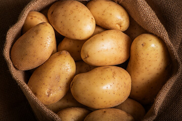 A sack full of potatoes for human consumption, top view, close-up.