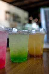 Italian soda made from fruit syrup drink mix in plastic cup on wood table