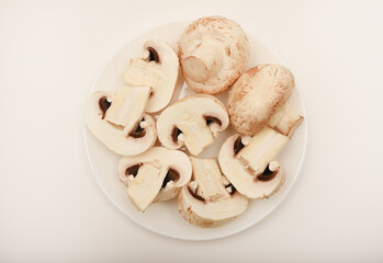 Fresh champignons on a white plate. Mushrooms on a white background.