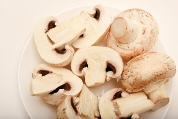 Fresh champignons on a white plate. Mushrooms on a white background.