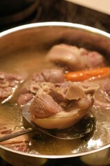 A close-up of pork shanks boiling in a pot with vegetables (golonka)