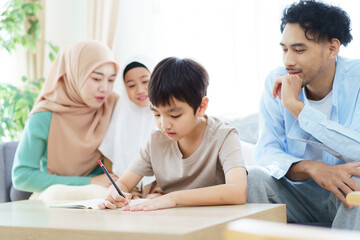 Fototapeta premium Asian muslim family relaxing in living room together.