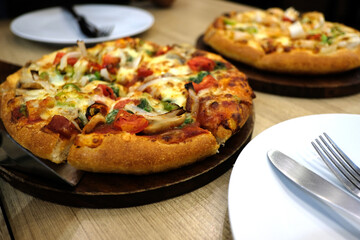 A vegetarian pizza and a seafood pizza are on a wooden table in a pizzeria