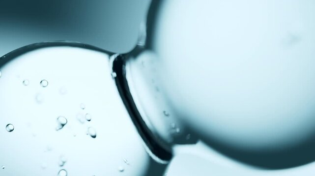 Macro shot of drops of pure fresh melt mountain water with tiny air bubbles, the drops are moving and merging into a large water sphere on a bright light blue background