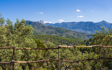 View through an old wooden fence over picturesque Mallorca mountain lanscape. Clear sky emphasizes natural beauty of landscape.