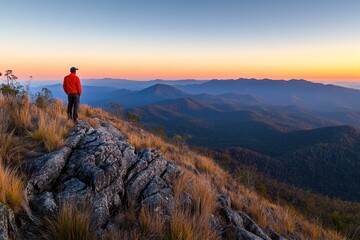 Obraz premium A man standing on top of the mountain, overlooking distant mountains and clear sky at sunrise with copy space for text. A hiker stands in awe as they look out over the vast landscape from atop Pui