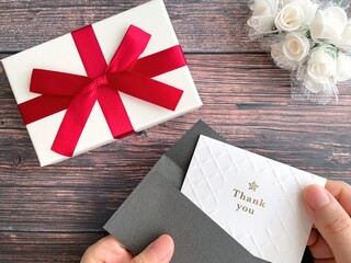 ギフトボックスとメッセージカードを持つ手元
