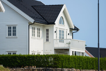 White modern wooden house with black roof.