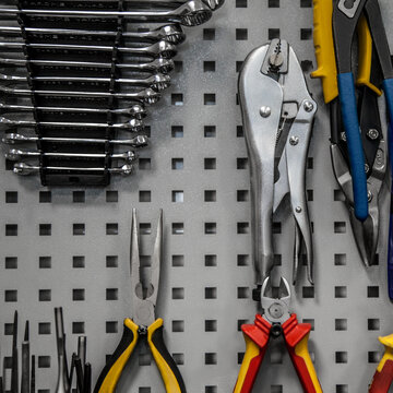 A neatly organized pegboard with various hand tools including wrenches, pliers, and locking pliers.