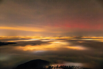 Feuerwerkslichter unter dem Nebelmeer. Silvester Feuerwerk 2024 und roter Aurora Borealis Polarlichter. Auf dem Breitenstein, Schwäbische Alb bei Ochsenwang. Blick Richtung Stuttgart und Hörnle.