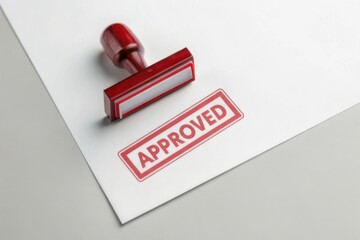 A red "APPROVED" stamp rests on a white sheet of paper, symbolizing validation or endorsement.