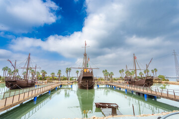 Naklejka premium Replica ships at Caravel Dock Museum. Wooden ships with masts and sails, docked in calm waters. Huelva, Spain.