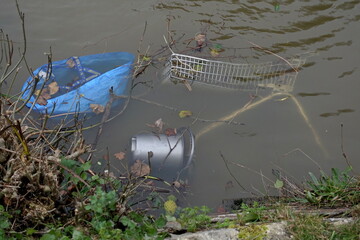 View of a shopping trolley and other items discarded in a town park pond