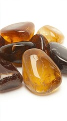Various polished amber stones display rich, warm hues and smooth surfaces against a clean white backdrop, highlighting their organic elegance