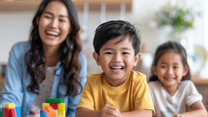 A joyful mother and her two children smile while playing with colorful building blocks in a bright, welcoming environment.