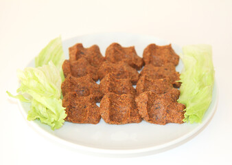 Delicious Turkish Specialty Food Cigkofte aka Spicy Bulgur Patties with Lettuce on plate on isolated white