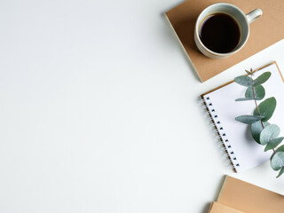 workspace with paper notebooks, coffee cup, eucalyptus leaves on Top view with copy space empty centre