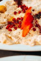 Close-Up of Creamy Hummus with Pomegranate and Tomato Garnish