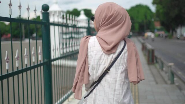 back view os asian muslim woman walking on the pedestrian walk