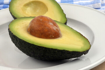 Avocat mûr coupé en deux avec son noyau dans une assiette en gros plan.