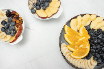 Top view of a breakfast spread featuring fresh fruits, glass of juice, blueberries, orange slices, apple slices, banana, and sunflower seeds, arranged neatly on plates. mindful eating and a balanced d