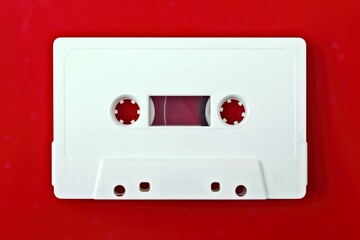White compact audio cassette isolated on red background with copy space.
