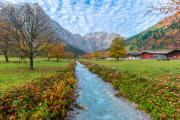 Colorful autumn landscape at Großer Ahornboden in the Karwendel Mountains, Austria – forest with fall foliage, rocky peaks and dramatic sky