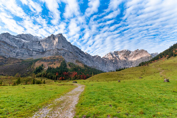 Colorful autumn landscape at Großer Ahornboden in the Karwendel Mountains, Austria – forest with fall foliage, rocky peaks and dramatic sky