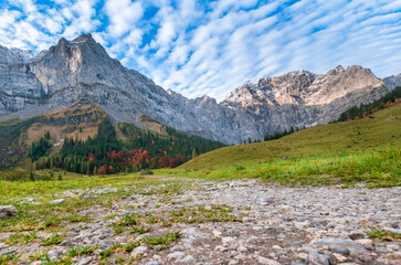 Colorful autumn landscape at Großer Ahornboden in the Karwendel Mountains, Austria – forest with fall foliage, rocky peaks and dramatic sky