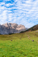 Colorful autumn landscape at Großer Ahornboden in the Karwendel Mountains, Austria – forest with fall foliage, rocky peaks and dramatic sky