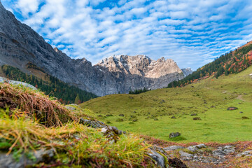 Colorful autumn landscape at Großer Ahornboden in the Karwendel Mountains, Austria – forest with fall foliage, rocky peaks and dramatic sky