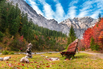 Colorful autumn landscape at Großer Ahornboden in the Karwendel Mountains, Austria – forest with fall foliage, rocky peaks and dramatic sky