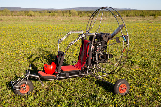Paragliding machine for paragliding flights on green grass against the bright sun. Preparing paralet with a gasoline engine for flights. Extreme sports