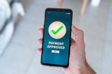 Payment approved notification on smart phone held by hand.
