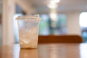 Close up of iced coffee plastic cup with a little ice on wood desk blurred background