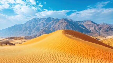 Desert sand dune, mountains, blue sky.