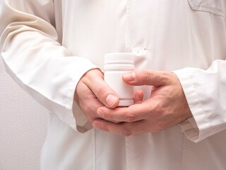 The doctor's hands are held in a white plastic pill jar. The recommendation of a doctor in a white coat